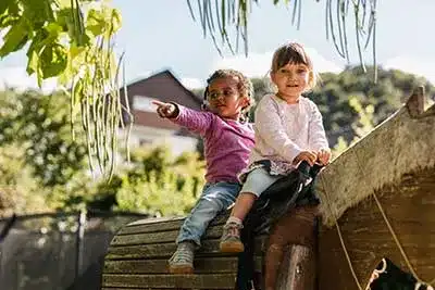 Zwei Mädchen spielen auf einem Holzpferd